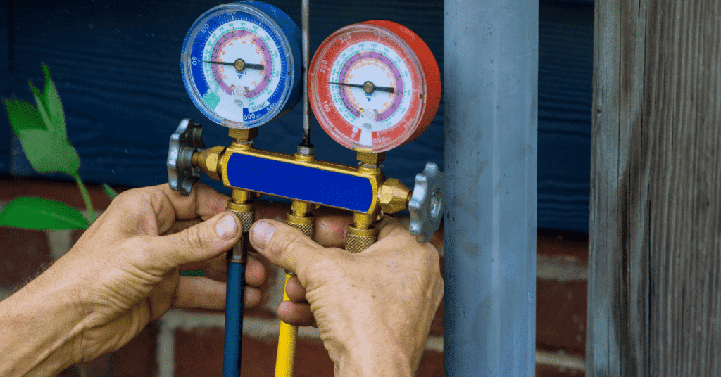 hvac technician checking refrigerant pressure with manifold gauges on outdoor air conditioning unit
